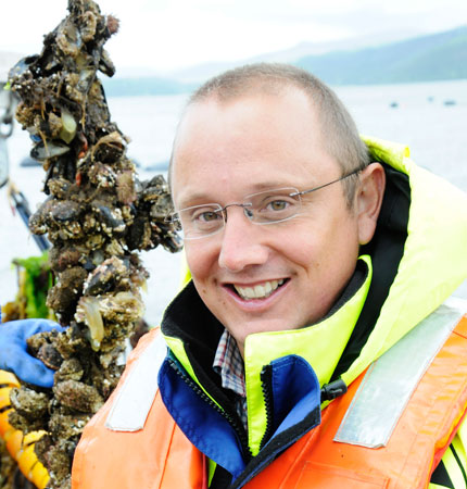 Adam Hughes on a marine farm with rope-grown mussels in the background